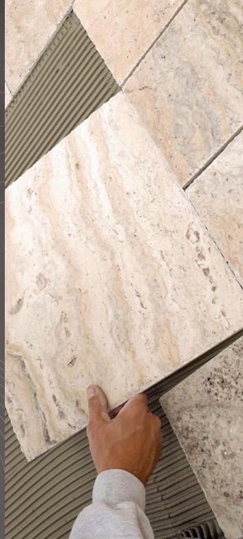 Master craftsman laying precision-fit marble floor tile with zero-tolerance joint alignment